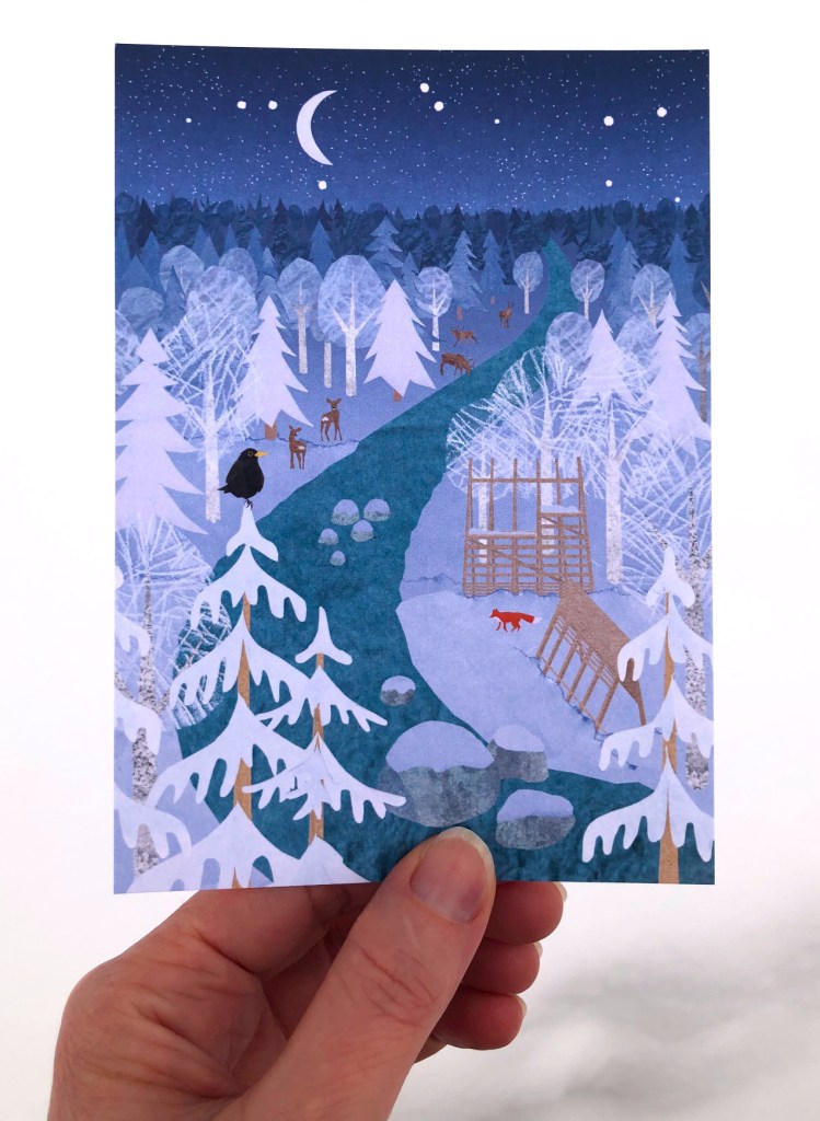 A white woman's hand holding an illustrated postcard. The illustration on the card is made using paper collage et digital collage. It shows a wintry landscape with a river flowing through a forest on a starry night. Wild animals are present along the banks of the river: reindeer, roe deer, a fox and a eurasian blackbird. A wooden weather shelter with a clean and modern design stands on the bank of the river. 